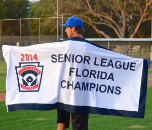 Largo Little League pitcher Kyle Koker proudly displays the team's championship banner.