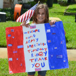 A young girl holds a sign at Timothy Riney's homecoming ceremony.
